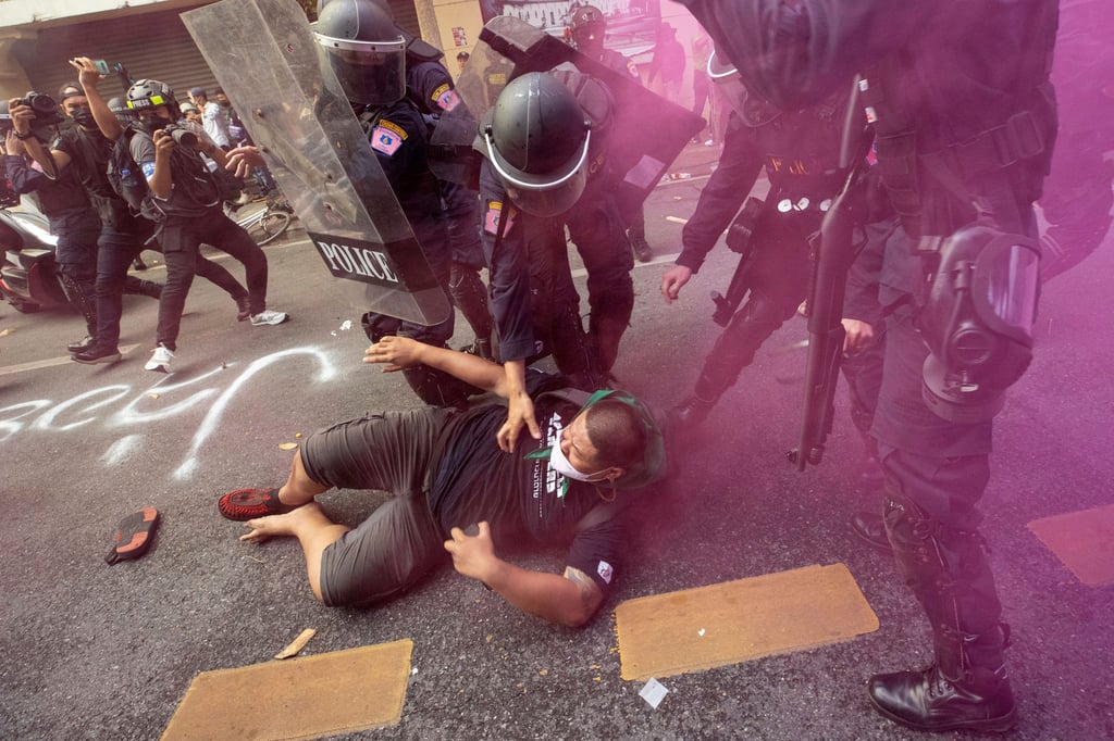 In a cloud of pink smoke, police remove protesters trying to march to the Apec summit venue. Photo: AP In a cloud of pink smoke, police remove protesters trying to march to the Apec summit venue. Photo: AP