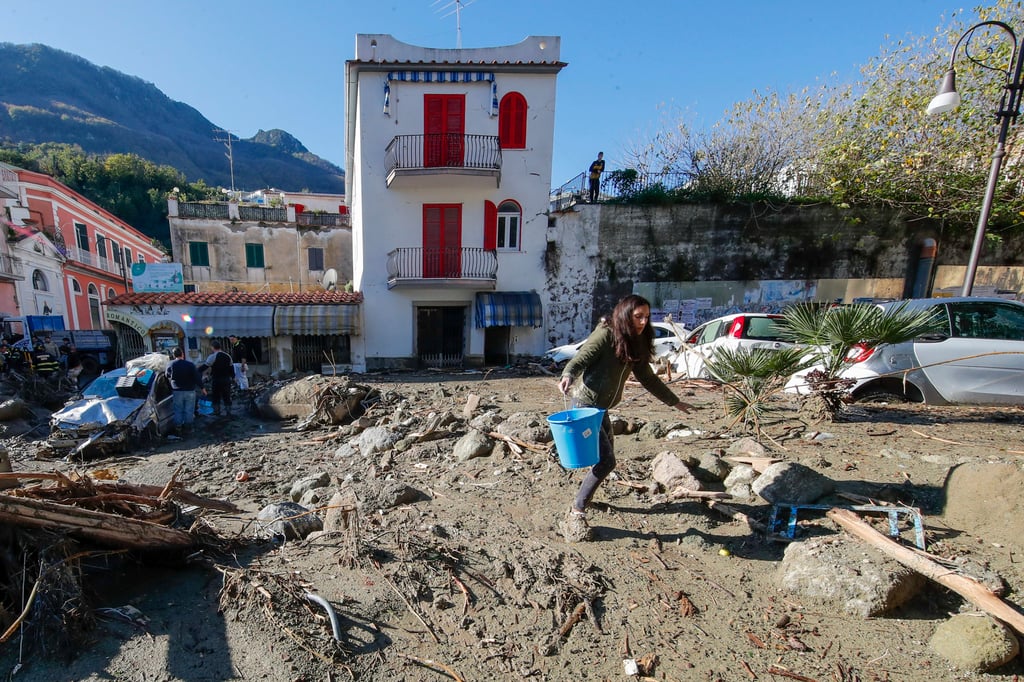 A woman removes mud and debris after heavy rain triggered fatal landslides that collapsed buildings on Saturday and left as many as 12 people missing on the Italian island of Ischia. Photo: AP A woman removes mud and debris after heavy rain triggered fatal landslides that collapsed buildings on Saturday and left as many as 12 people missing on the Italian island of Ischia. Photo: AP