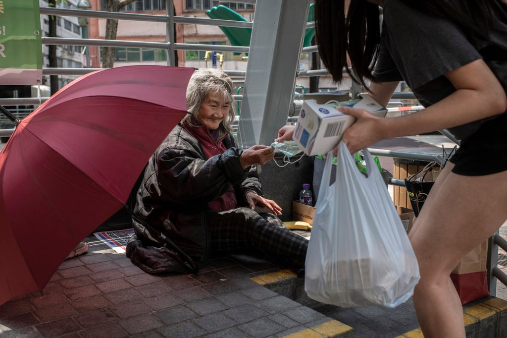 A volunteer with ImpactHK delivers masks and other goods to an elderly woman experiencing homelessness during a “Kindness Walk” in Hong Kong. A volunteer with ImpactHK delivers masks and other goods to an elderly woman experiencing homelessness during a “Kindness Walk” in Hong Kong.