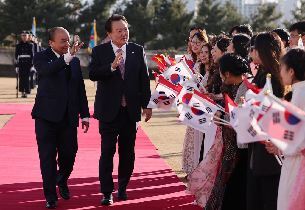 Vietnamese President Nguyen Xuan Phuc (left) and South Korean President Yoon Suk-yeol wave at well-wishers carrying national flags of the two nations during a welcoming ceremony at the presidential office in Seoul on Monday. Photo: Yonhap via AP