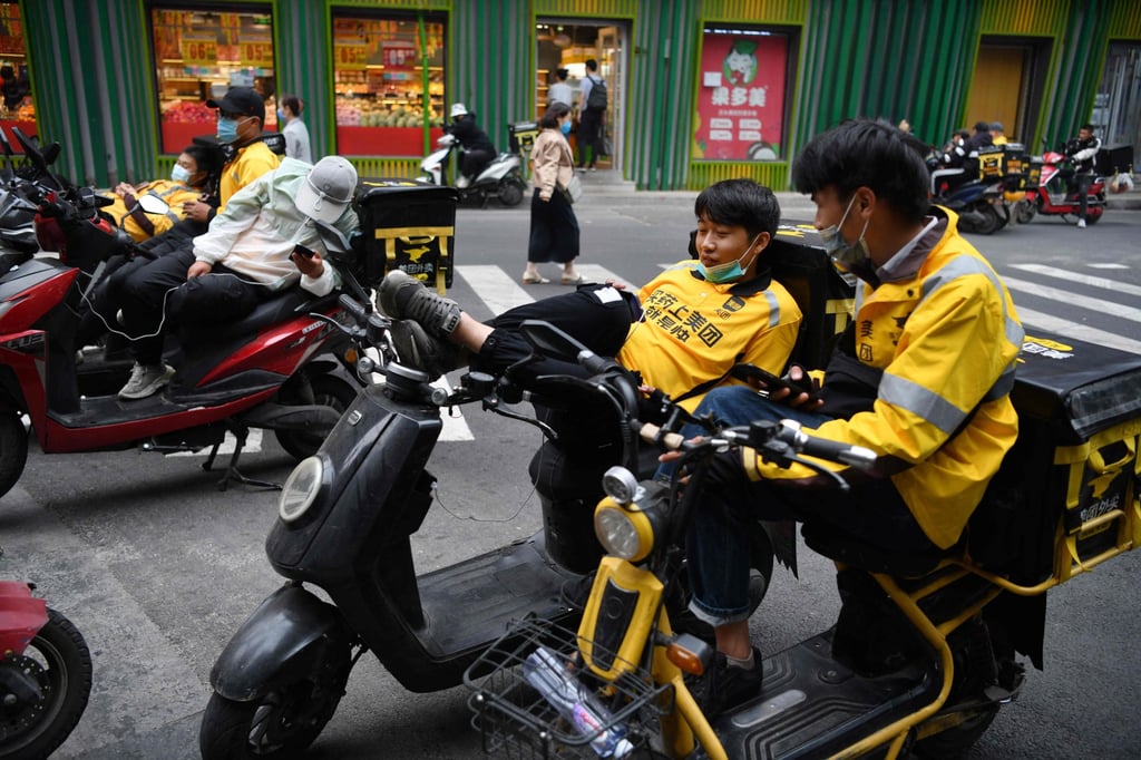 Delivery riders for Meituan wait for orders outside a restaurant in Beijing. Photo : AFP