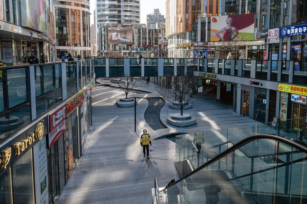 A delivery worker walks through an empty shopping area in Beijing on December 23, 2022. Soaring Covid-19 infections are keeping people home and causing a slump in travel and economic activity, according to the latest high-frequency data. Photo: Bloomberg