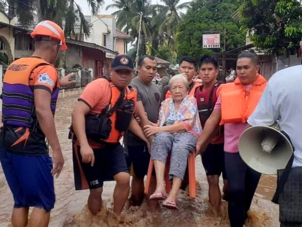 Rescuers carry an elderly woman to safety in the town of Plaridel on December 26. Photo: Philippine Coastguard Handout via EPA-EFE