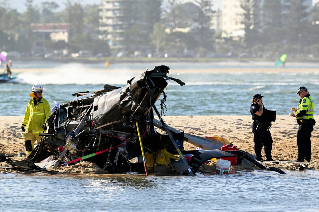 Emergency workers inspect a helicopter at the scene of a collision on the Gold Coast. Photo: AAP Image via AP