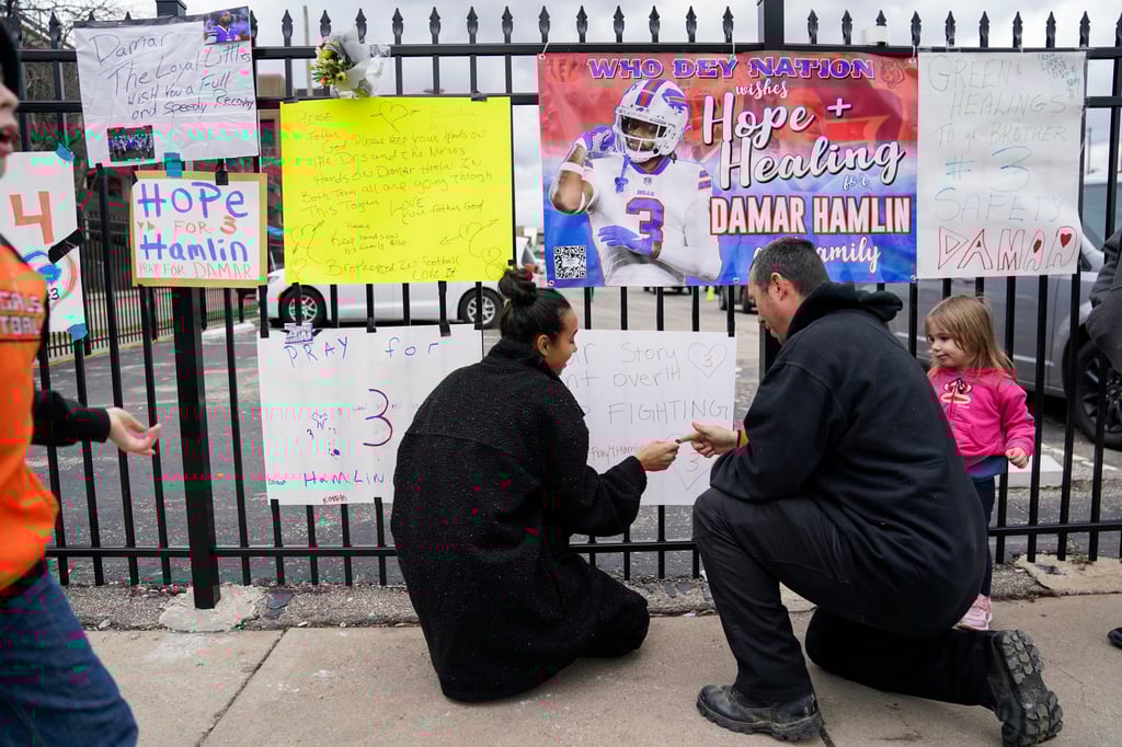 Kayla Adeniji (centre), wife of Cincinnati Bengals offensive lineman Hakeem Adeniji, tapes up a sign she made in support of Damar Hamlin. Photo: AP