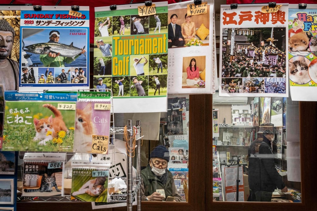 A man counts cash at a calender shop in Tokyo on January 5, 2023. People were still advised to wear masks when indoors, except in cases where social distancing of two metres or more is secured and where there is virtually no conversation. Photo: AFP