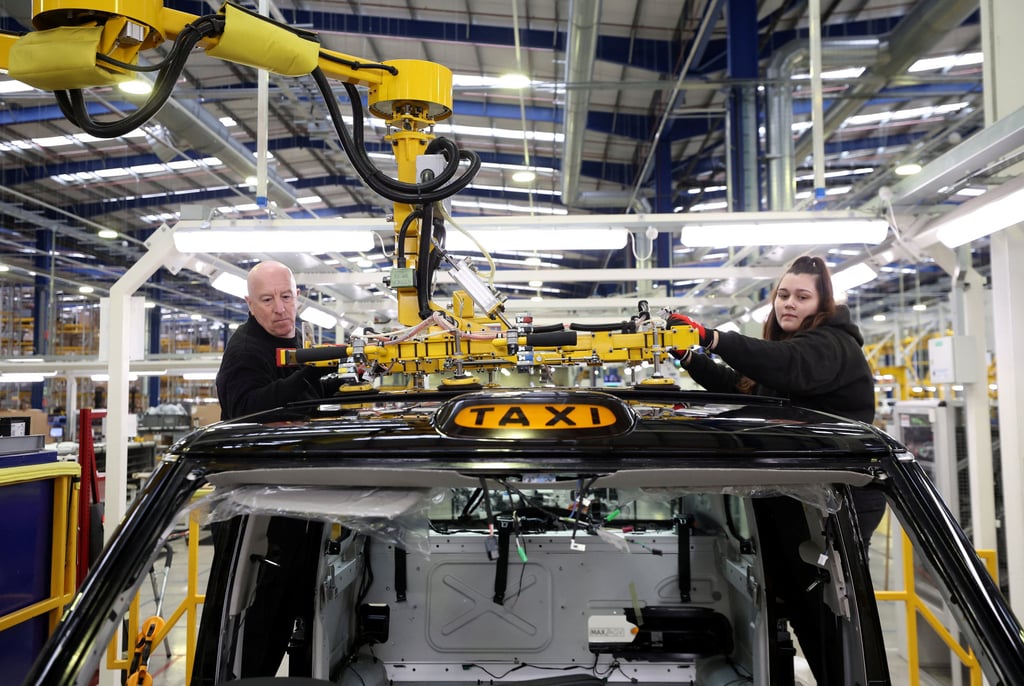 Workers fit a roof panel on the TX electric taxi production line inside the LEVC factory in Coventry, England. Photo: Reuters