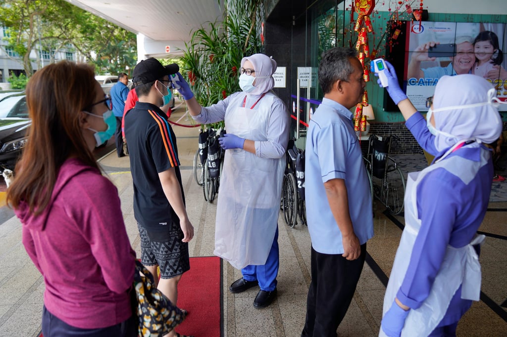 Nurses check the temperatures of visitors as part of the coronavirus screening procedure at a hospital in Kuala Lumpur, Malaysia, in February 2020. Photo: AP Nurses check the temperatures of visitors as part of the coronavirus screening procedure at a hospital in Kuala Lumpur, Malaysia, in February 2020. Photo: AP