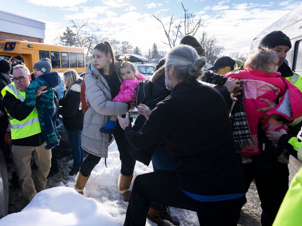 Parents and their children are loaded onto a warming bus as they wait for news after a bus crashed into a day care centre in Laval, Quebec, on Wednesday. Photo: The Canadian Press via AP