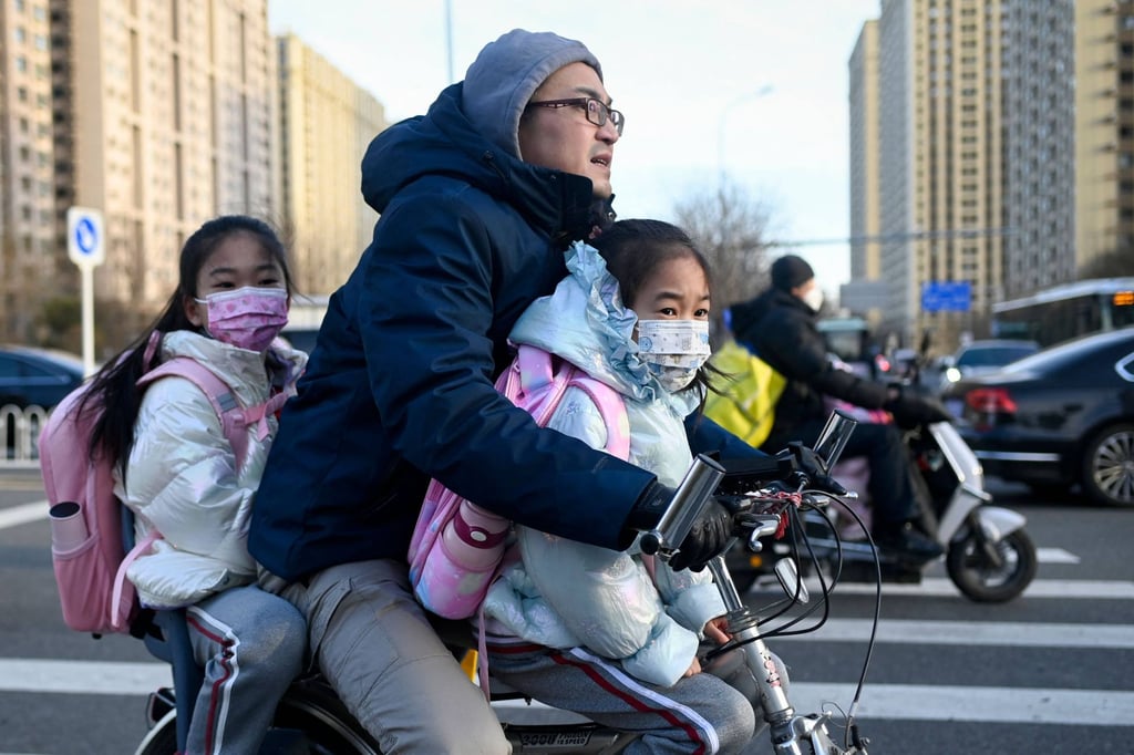 Travellers on a bicycle as children head for classes in Beijing. Photo: AFP
