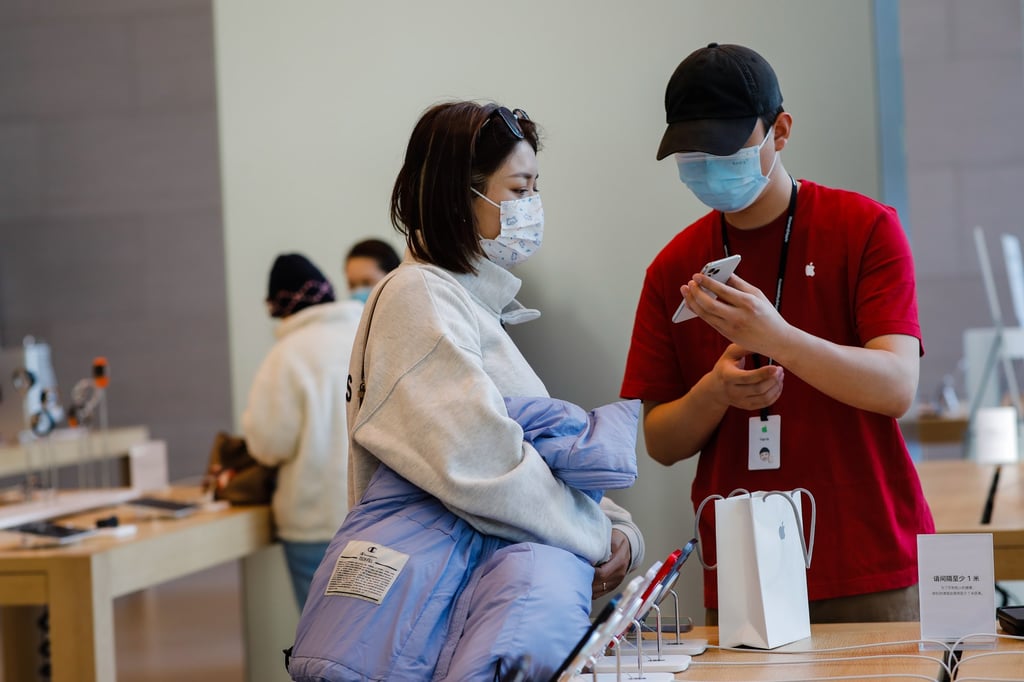 A shopper looks at an iPhone 14 model held by an Apple Store employee at a mall in Beijing on November 7, 2022. Apple led smartphone sales in China in the fourth quarter last year. Photo: EPA-EFE