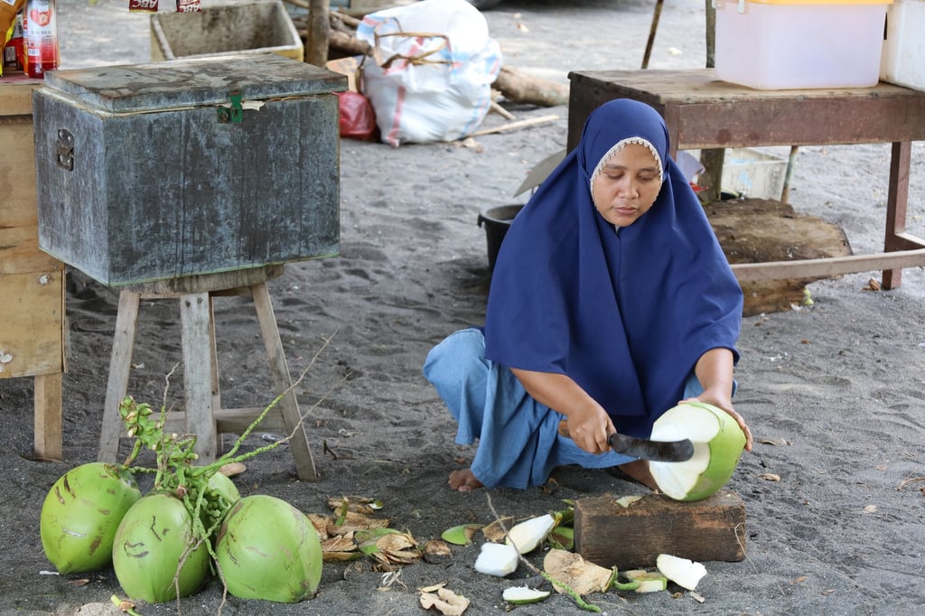 A local woman cuts a coconut on the Indonesian island of Lombok. Photo: Thomas Bird