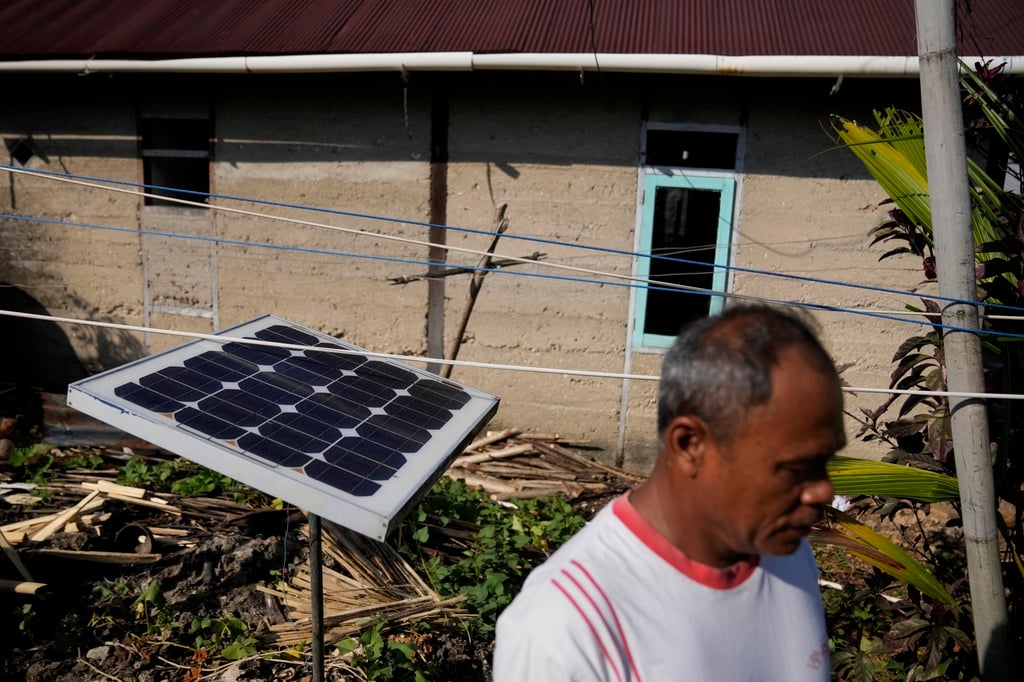 A man walks past a small solar panel he uses for back up, outside his house on Karampuang Island, in West Sulawesi. Photo: AP