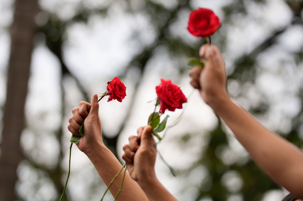 Protesters raise their clenched fists while holding red roses in the Philippines as they mark International Women’s Day. Photo: AP Protesters raise their clenched fists while holding red roses in the Philippines as they mark International Women’s Day. Photo: AP
