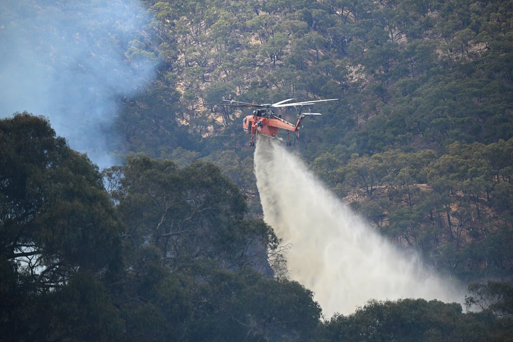 A firefighting helicopter works to extinguish blazes in Australia in February when a large and fast-moving grass fire north of Melbourne was expanding and heading towards towns. Photo: EPA-EFE A firefighting helicopter works to extinguish blazes in Australia in February when a large and fast-moving grass fire north of Melbourne was expanding and heading towards towns. Photo: EPA-EFE
