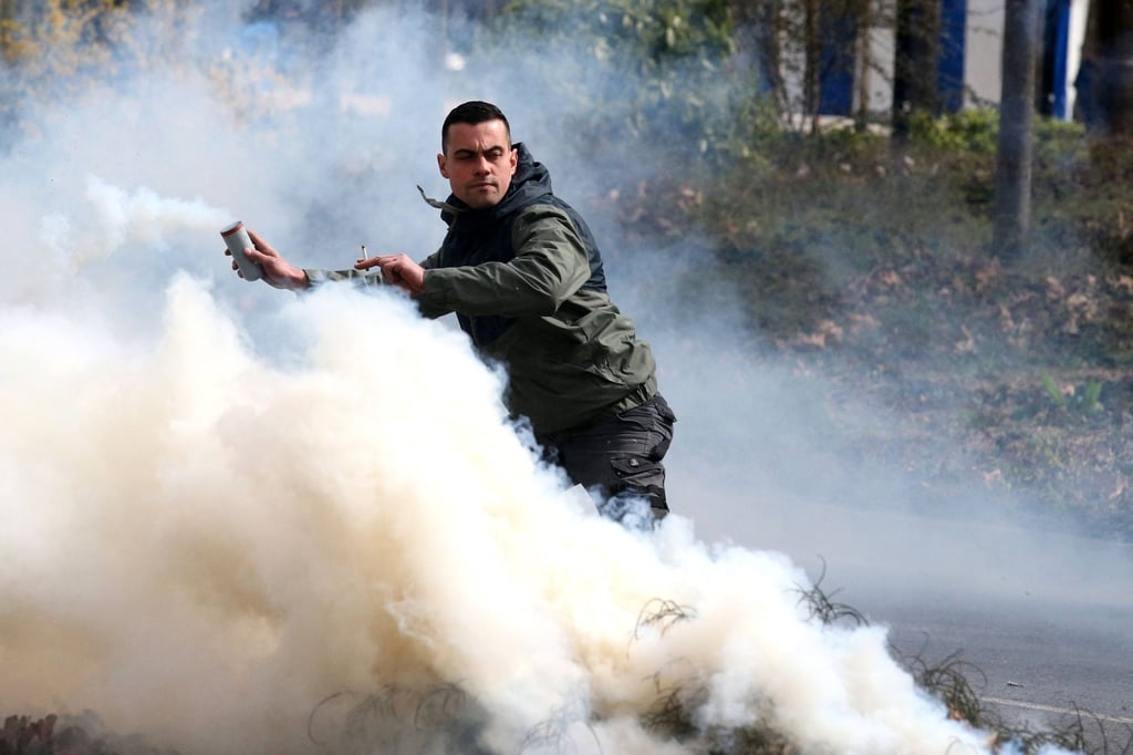 A demonstrator holds a smoke flare during a protest against the French government pushing a pensions reform through parliament without a vote. Photo: AFP