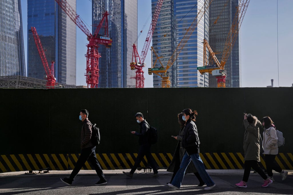 People walk by construction cranes near office buildings at the central business district in Beijing on March 15. China’s reopening should allow it to achieve growth of over 5 per cent this year. Photo: AP