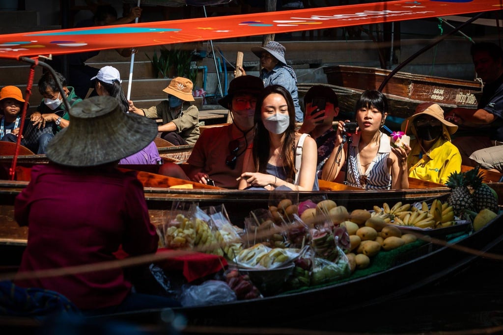 Tourists on a sampan ride past a fruit vendor at a floating market in Thailand. Photo: Bloomberg