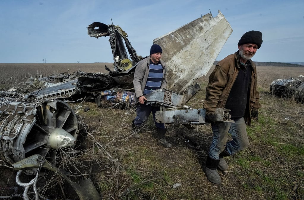 Local residents carry collected scrap metal near a destroyed military plane in Ukraine’s Kharkiv region on Saturday. Photo: Reuters