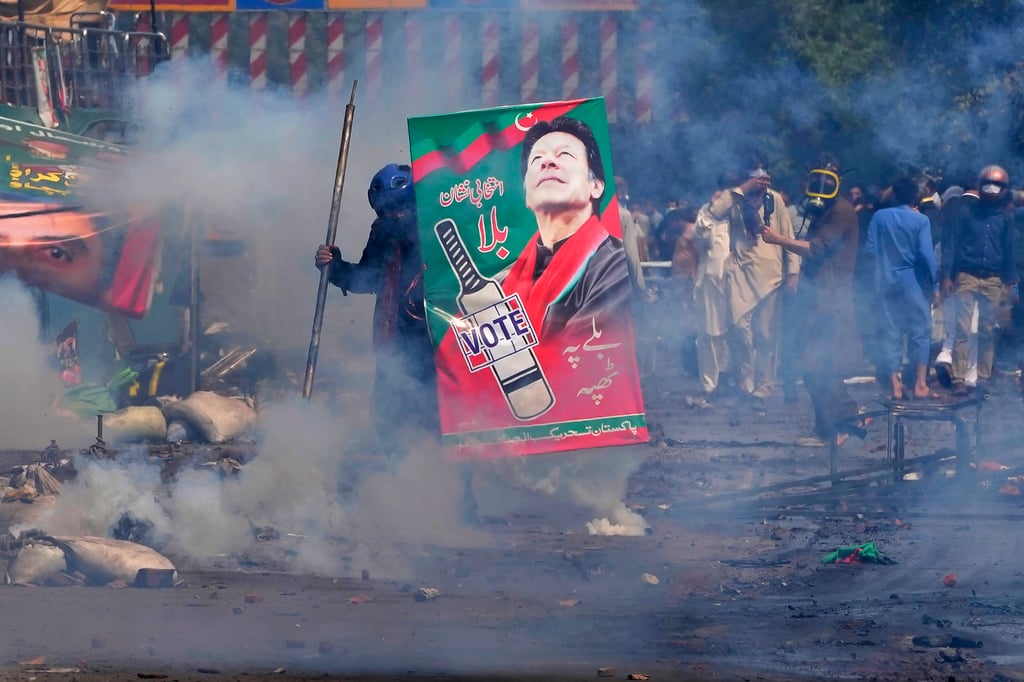 Supporters of former Prime Minister Imran Khan take cover after riot police fire tear gas to disperse them during clashes in Lahore last month. Photo: AP
