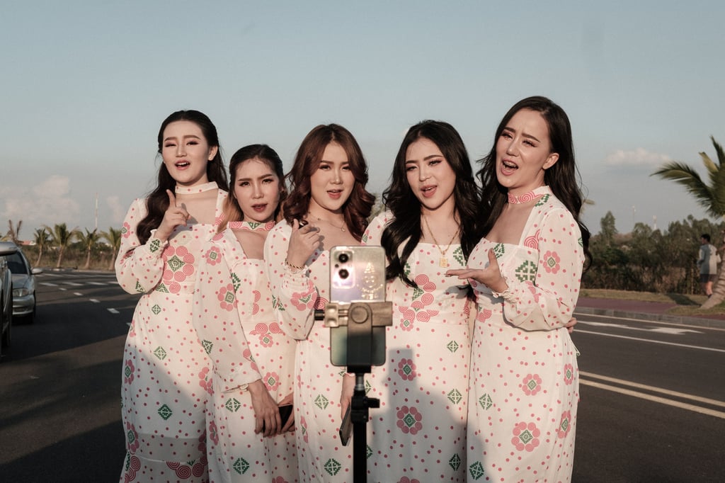 Influencers shoot a live video on TikTok beside That Luang artificial lake. Photo: Nicholas Bosoni