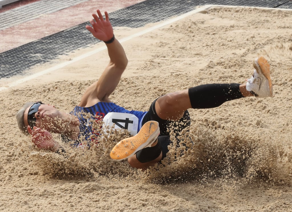 Ko Ho-long lands in the sand after a jump at the 2023 Hong Kong Athletics Championships. Photo: Jonathan Wong