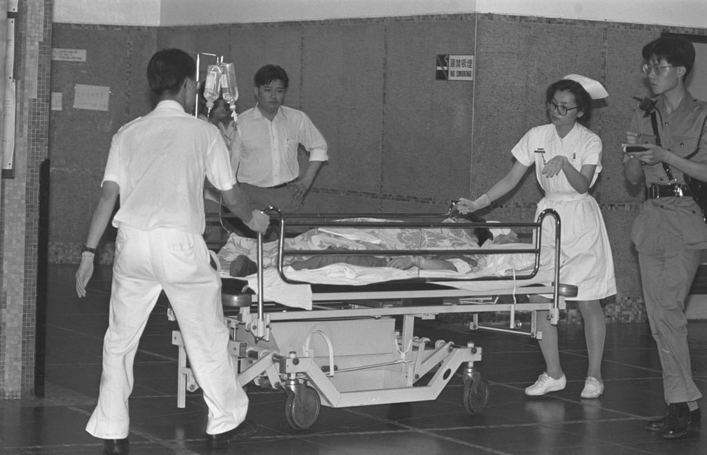 Nurses, escorted by a policeman, move one of the victims of the armed robbery at a Mong Kok mahjong parlour. Photo: SCMP