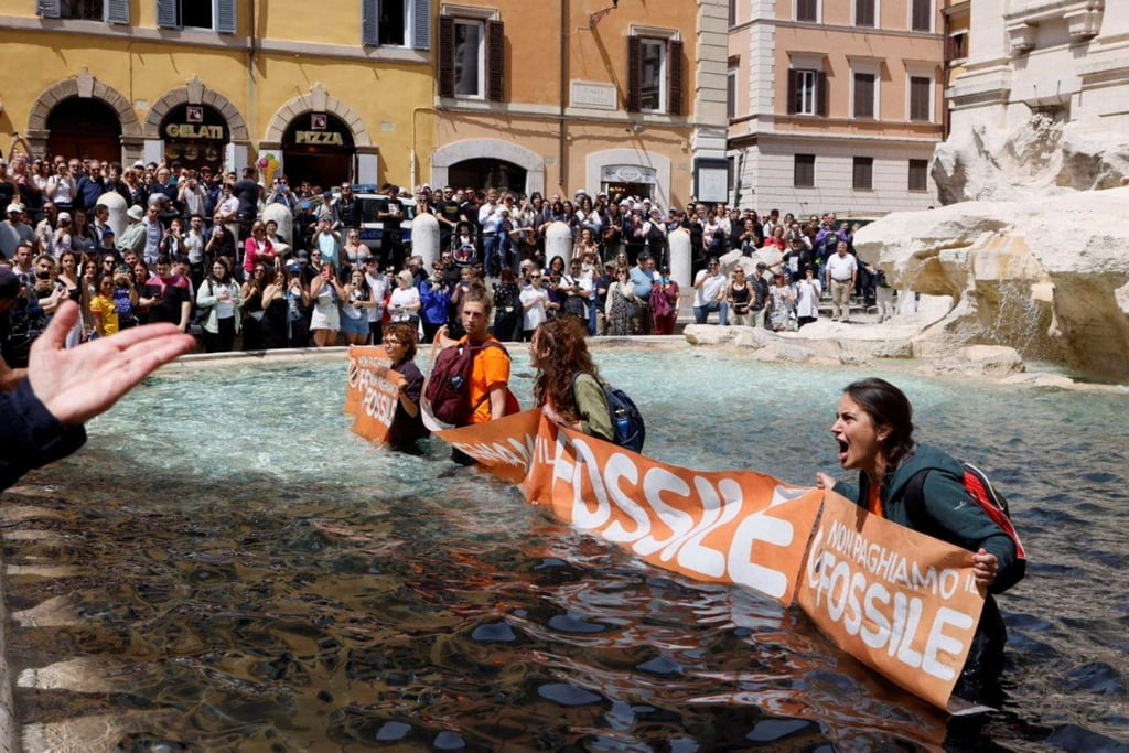Climate activists hold a banner after pouring charcoal in the Trevi Fountain water in Rome, Italy on Sunday. Photo: Alessandro Penso / MAPS via Reuters