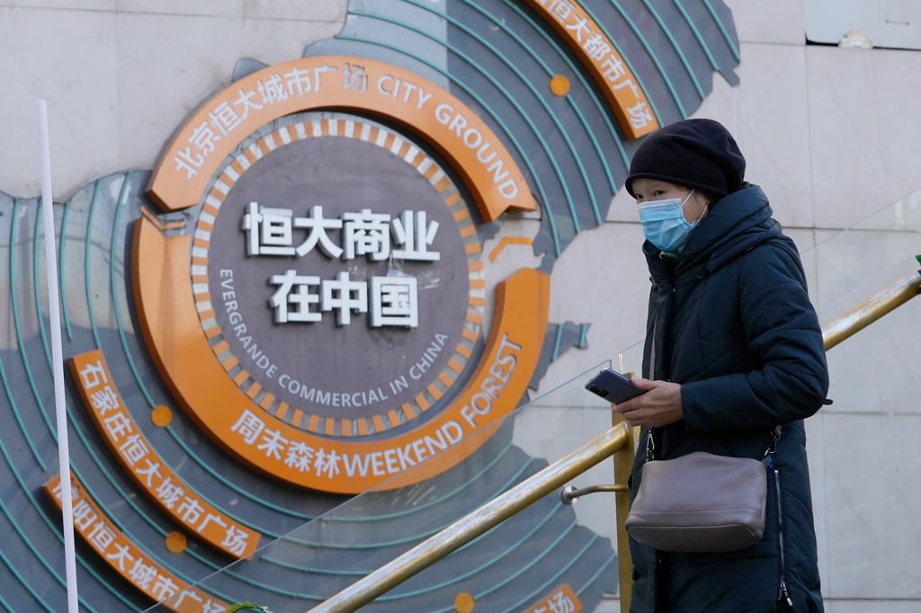 A woman passes by a display showing Evergrande’s China commercial projects in Beijing, China. Photo:AP