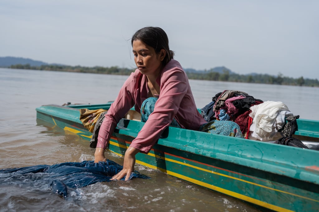 Tha Sara, a widow with three children, washes her clothes from a boat moored on the banks of the Mekong, near Veun Sien village, Stung Treng province. Photo: Andy Ball Tha Sara, a widow with three children, washes her clothes from a boat moored on the banks of the Mekong, near Veun Sien village, Stung Treng province. Photo: Andy Ball