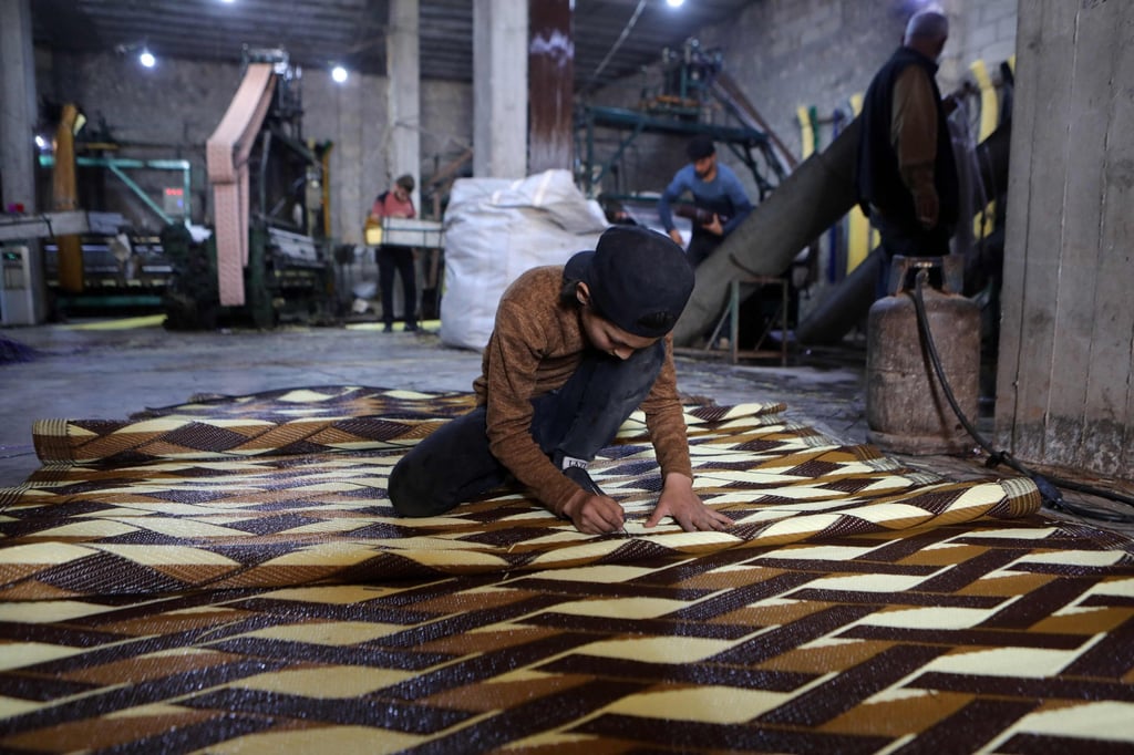 A child works at a factory making mats and rugs from recycled plastic, in Sarmada in Syria’s northwestern Idlib province. Photo: AFP
