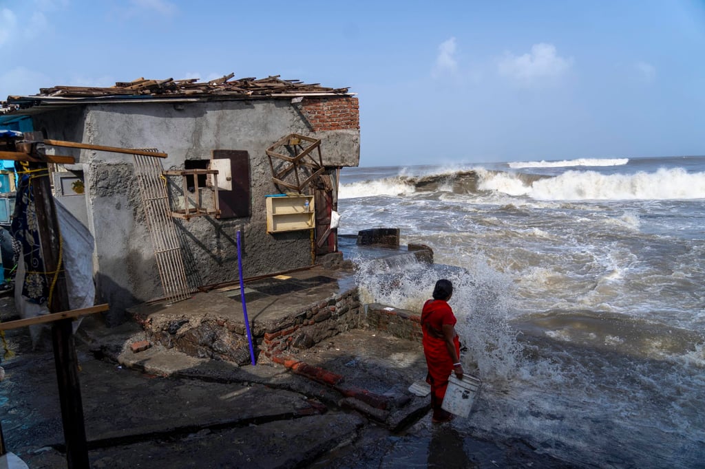 A woman stands next to her house as high tide waves hit the Arabian Sea coast in Mumbai, India. Photo: AP A woman stands next to her house as high tide waves hit the Arabian Sea coast in Mumbai, India. Photo: AP
