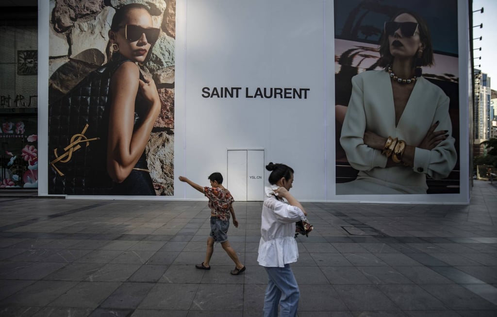 Pedestrians pass a billboard for Yves Saint Laurent in Chongqing, China. Photo: Bloomberg Pedestrians pass a billboard for Yves Saint Laurent in Chongqing, China. Photo: Bloomberg