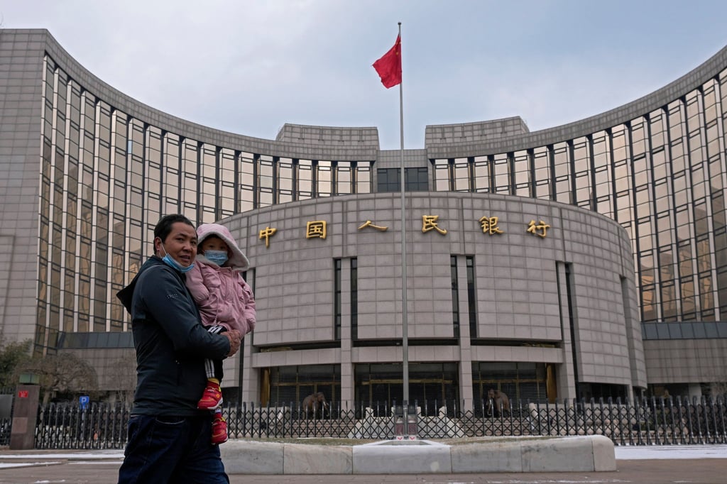 A man carries a child in front of China’s central bank in Beijing. Photo: AP A man carries a child in front of China’s central bank in Beijing. Photo: AP