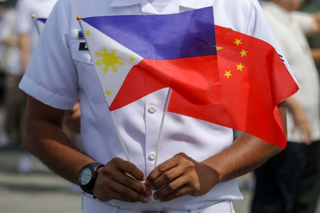 A member of the Philippine coastguard holds the national flags of the Philippines and China to mark the arrival of a Chinese naval training ship on a goodwill visit earlier this month. Photo: AP