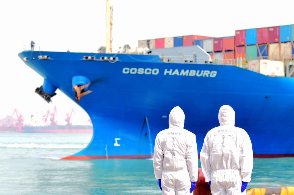 Port employees in protective suits watch a loaded container ship at Qingdao port in Shandong on April 1, 2020. China’s maritime industry, like the rest of the country’s economy, is still recovering from the effects of the Covid-19 pandemic. Photo: DPA