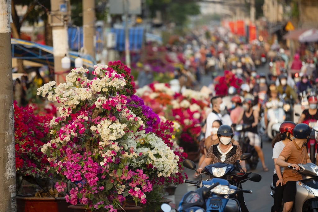 Motorcyclists drive past the flower market at Binh Dong Wharf in Ho Chi Minh City, Vietnam, on January 29, 2022. Vietnam’s central bank is among those that have reduced borrowing costs in the last three months. Photo: Bloomberg