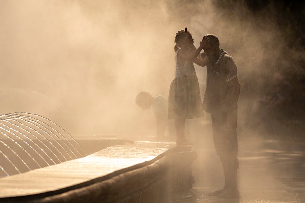 A little girl and her father seek relief from heat in mist from a public fountain in Bucharest, Romania, on July 13, 2023, as the temperature exceeds 40 degrees Celsius. Photo: AP A little girl and her father seek relief from heat in mist from a public fountain in Bucharest, Romania, on July 13, 2023, as the temperature exceeds 40 degrees Celsius. Photo: AP