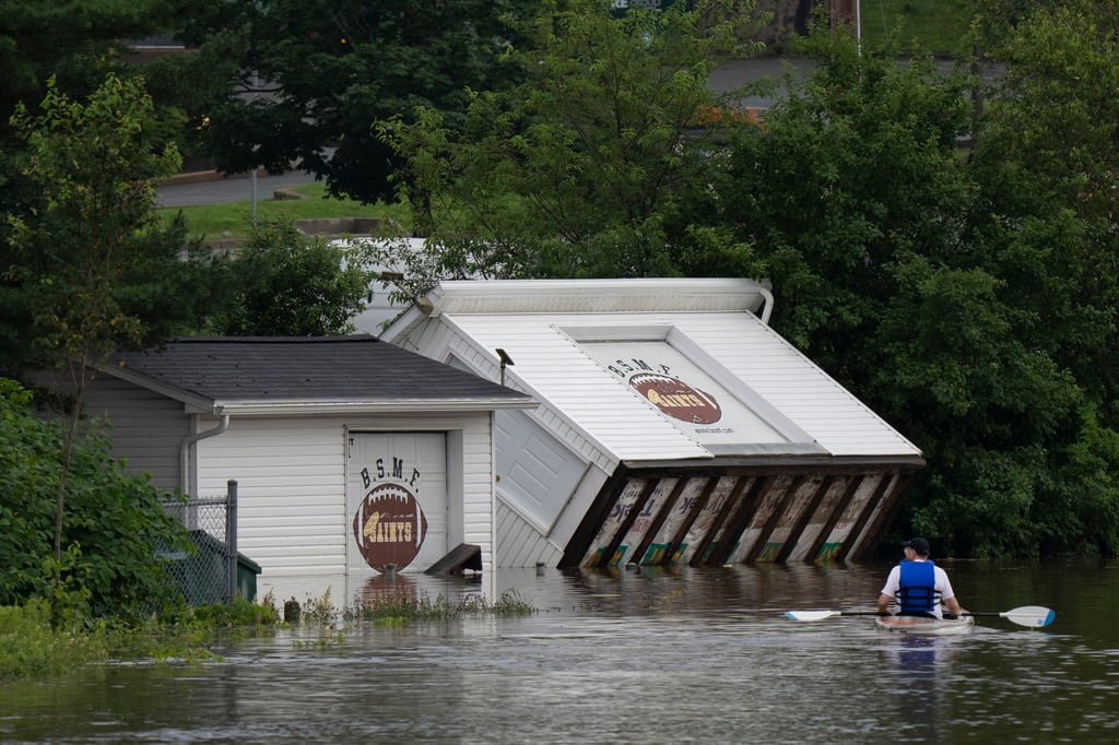 Buildings upended on a riverbank as a man paddles a kayak through floodwater in Halifax, Nova Scotia, Canada on Saturday. Photo: The Canadian Press via AP
