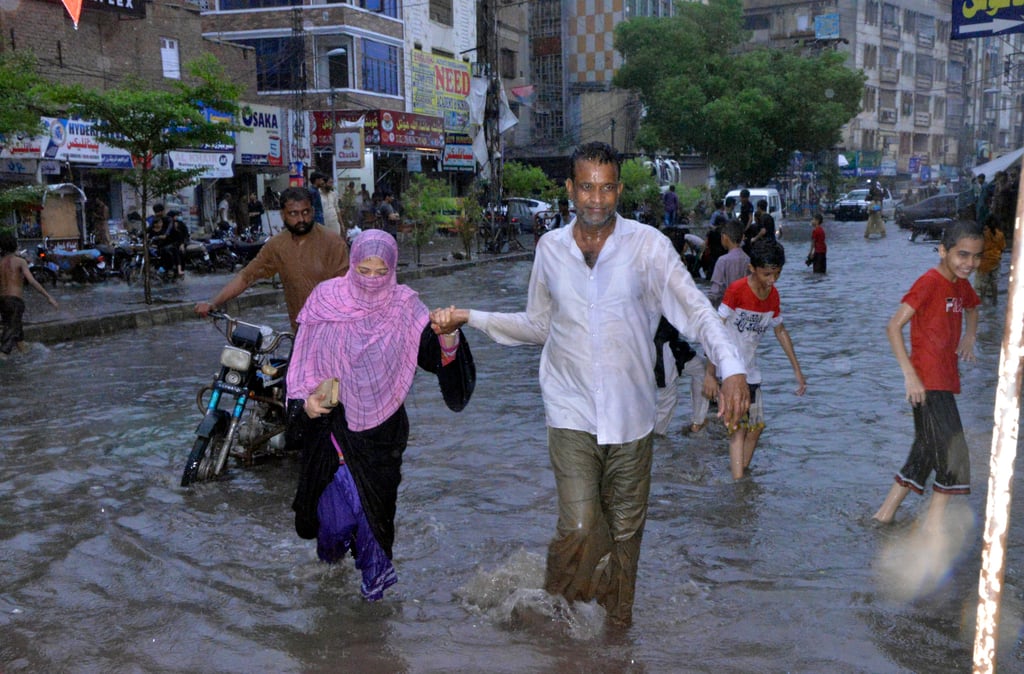 People wade through a flooded area caused by heavy monsoon rainfall in Karachi, Pakistan on Sunday. Photo: AP