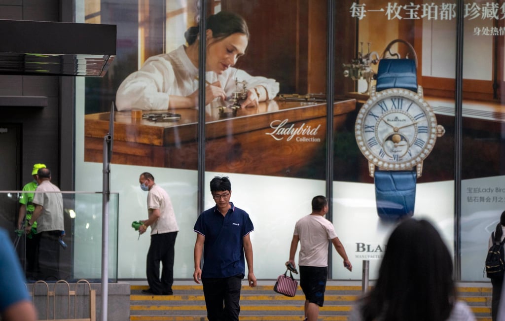 People walk past a billboard for Swiss luxury watch retailer Blancpain at a shopping centre in Beijing in June. Photo: AP People walk past a billboard for Swiss luxury watch retailer Blancpain at a shopping centre in Beijing in June. Photo: AP