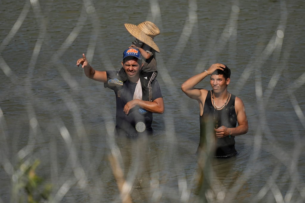 Migrants stand in the Rio Grande behind concertina wire as they try to enter the US from Mexico. Photo: AP Migrants stand in the Rio Grande behind concertina wire as they try to enter the US from Mexico. Photo: AP