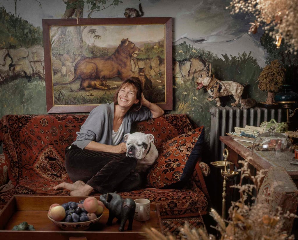Jane Mallory Birkin poses on a sofa covered with an oriental woven carpet with her British bulldog by her side in the salon of her former home in Paris, France. Photo: Getty Images