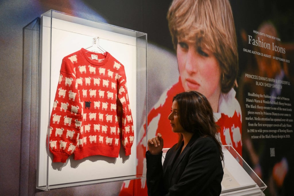 A staff member poses with the “black sheep” jumper” designed by Sally Muir and Joanna Osborne and worn on several occasions by Britain’s late Princess Diana during a press view at Sotheby’s auction house in London, on July 17. Photo: AFP