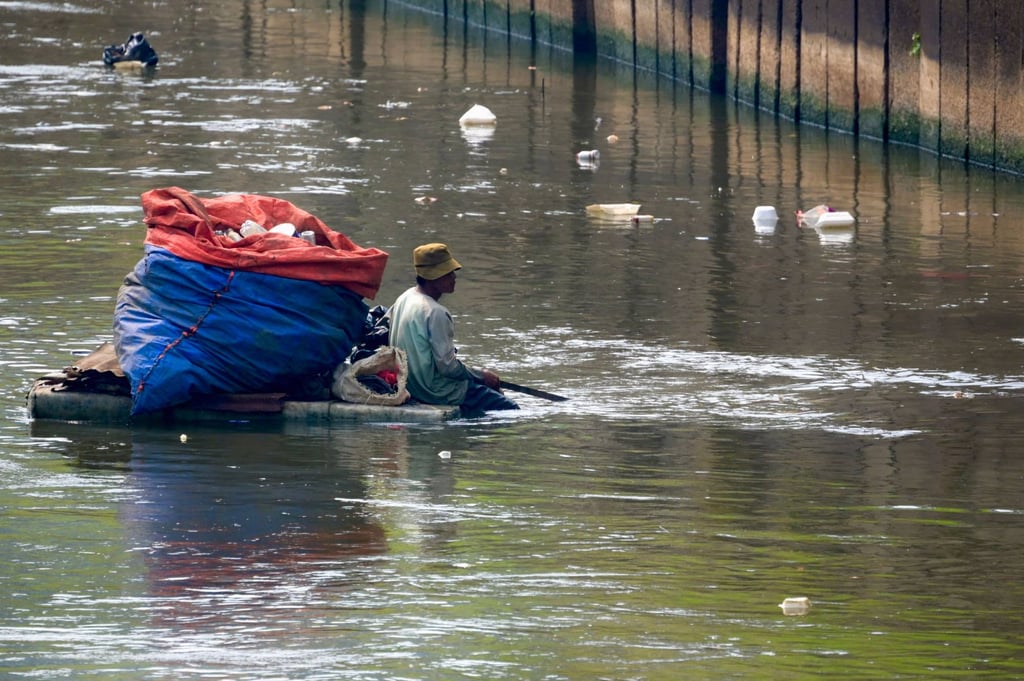 A man on a wooden raft looks for plastic waste to sell at a recycling site in Jakarta. Photo: AFP A man on a wooden raft looks for plastic waste to sell at a recycling site in Jakarta. Photo: AFP