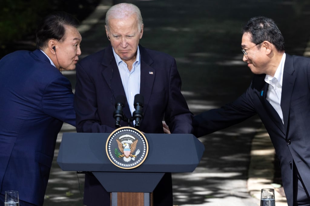 Yoon (left) and Kishida shake hands across Biden at their news conference in Maryland. Photo: EPA-EFE Yoon (left) and Kishida shake hands across Biden at their news conference in Maryland. Photo: EPA-EFE