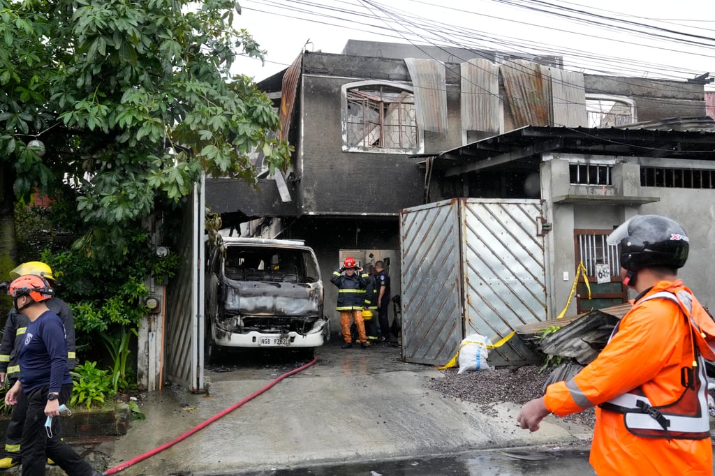 Firefighters check a factory that caught fire killing more than a dozen people on Thursday in a small apparel factory in a Philippine residential area. Photo: AP