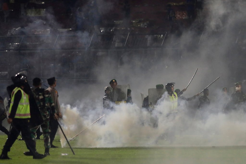 Police officers and soldiers stand amid tear gas smoke at Kanjuruhan Stadium in Malang, East Java on October 1, 2022. Photo: AP