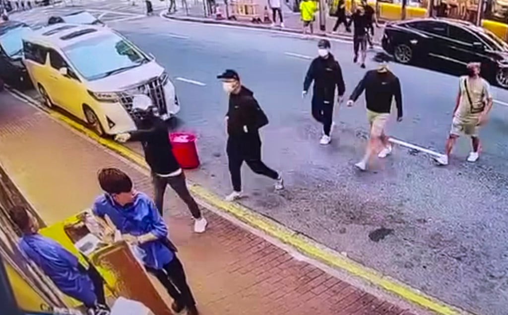 Online footage shows a group crossing Castle Peak Road in Cheung Sha Wan before pushing over a booth guarded by two mahjong parlour workers. Photo: Handout Online footage shows a group crossing Castle Peak Road in Cheung Sha Wan before pushing over a booth guarded by two mahjong parlour workers. Photo: Handout
