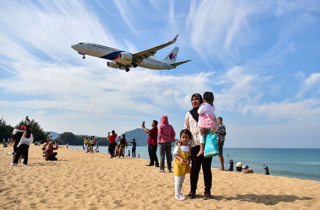 Tourists on Phuket’s Mai Khao beach as a plane lands at the airport. The tourism-dependent country’s sandy beaches have drawn 18.5 million foreign visitors, including more than 2 million Chinese, so far this year. Photo: AFP